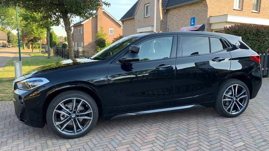 De BMW X2 van Autorijschool Mulders van opzij, met de L op de daklichtbak